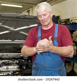 A Motor Mechanic Cleaning His Greasy Hands After Servicing A Car. Focus On His Hands