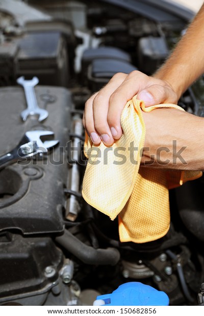 Motor mechanic cleaning his greasy hands after\
servicing car
