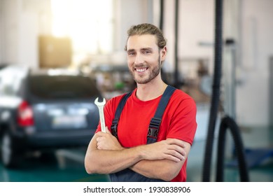 Motor Mechanic. Joyful Young Bearded Man Motor Mechanic In Overalls With Tool Standing In Workshop