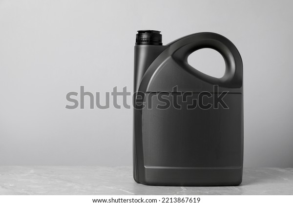Motor oil in grey canister on grey marble\
table against light background, space for\
text