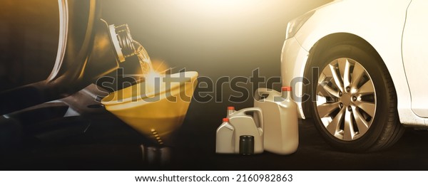 Motor oil pouring to engine with a yellow\
funnel,white car and motor oil bottle on black\
background,Automobile repair shop business\
concept