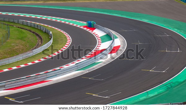 Motor racing circuit Red and\
White Kerb. A race track bend with grid signs and wheel\
arches.