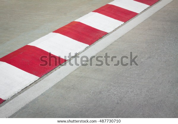 Motor racing circuit Red and White. White and\
red strip no Parking Sign on Footpath road. Road sign. Red and\
White sign on road. Motor race asphalt.  white and red of concrete\
road texture background.