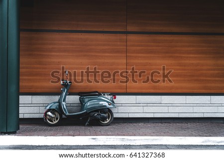 motor scooter parked in front of a building wall