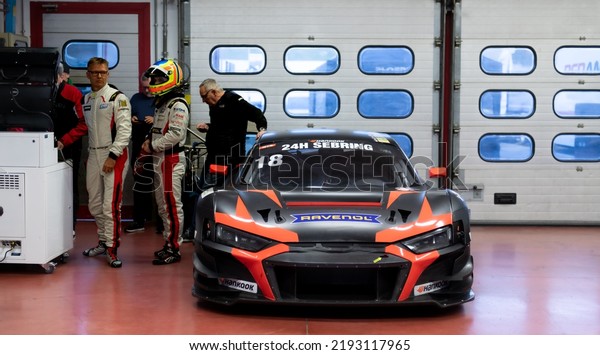 Motor sport scene, Audi R8 super car GT race\
standing in team garage with people and driver. Mugello, Italy,\
march 25 2022. 24 Hours\
series