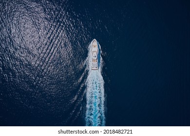 Motor Yacht In Motion Top View. A Huge Super Mega Yacht In White On Dark Blue Water In Italy. White Yacht On The Sea Aerial View. Superyacht Is Moving Fast On The Water Top View.