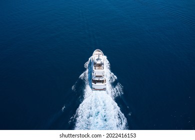 Motor Yacht In Motion Top View. Superyacht Is Moving Fast On The Water Top View. A Huge Super Mega Yacht In White On Dark Blue Water In Italy. White Yacht On The Sea Aerial View.