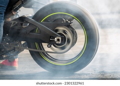 Motorbike burning tire rubber on road, Motorbike wheel drifting and white smoking on track, Motorcycle wheel on racing track with white smoke.