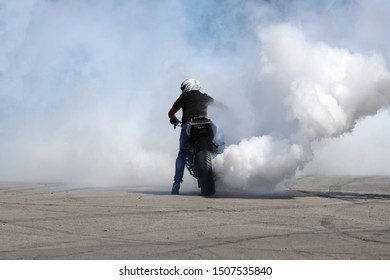 Motorbike burns wheel on a race track. White smoke.