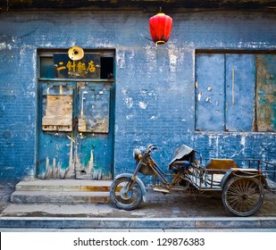 Motorbike cart parked in front of the decaying blue facade of an abandoned shop in Pingyao, China - Powered by Shutterstock