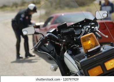 Motorbike with police officer talking with driver in the background - Powered by Shutterstock
