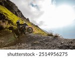 Motorbiker posing on motorbike in Italian Alps during sunrise, dramatic sky. Travel and freedom, outdoor activities