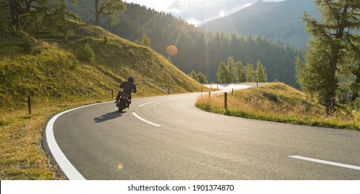 Motorbiker riding in Austrian Alps in beautiful sunset dramatic sky. Travel and freedom, outdoor activities