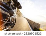 Motorbiker riding in Italian Alps during sunrise, dramatic sky . Travel and freedom , outdoor activities , side view .