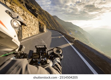 Motorbiker riding in Italian Alps during sunrise, handlebar view, dramatic sky. Travel and freedom, outdoor activities - Powered by Shutterstock