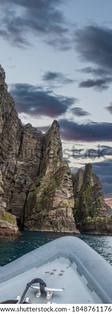 Motorboat near huge cliffs under cloudy sky for
text space
