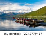 Motorboats lined up on a dock reflected in a beautiful lake with snow-capped mountains in the background at Lake McDonald in Glacier National Park
