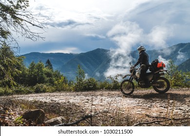 motorcycle adventure on the summit of the mountain, enduro, off road, beautiful view, danger road in mountains clouds, rider, dual sport