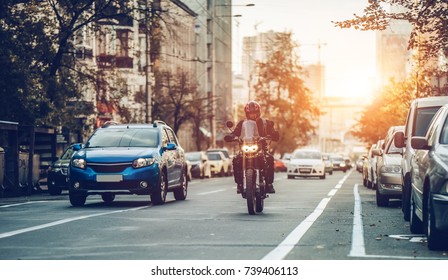 Motorcycle and cars are riding on street. City during the sunset. - Powered by Shutterstock