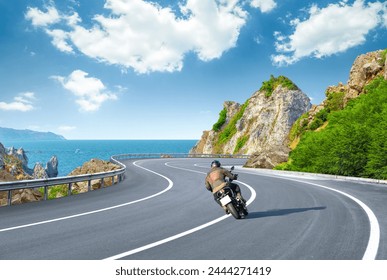 motorcycle drive on the France coastal road landscape in summer. Riding a motorcycle is freedom. motorbike driver is speeding along the holiday road. Sea view on highway on the Mediterranean beach.