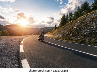 Motorcycle driver riding in Alpine road, Austria, Europe. Outdoor photography, mountain landscape. Travel and sport photography. Speed and freedom concept