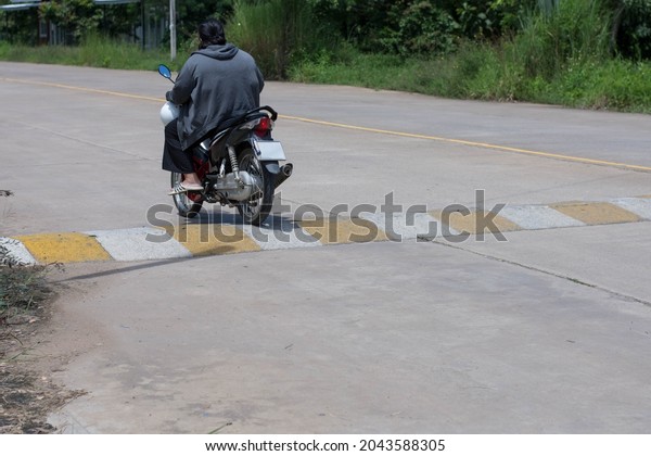 motorcycle driving up to Speed Bump on road.Traffic\
safety speed bump.