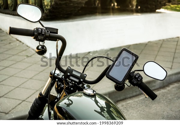 motorcycle with electronic dashboard gps on\
the steering wheel. mobile phone in cover.\
