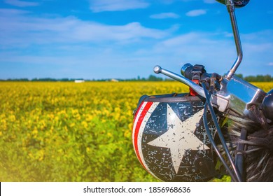 Motorcycle helmet hanging on the steering wheel against the background of a field with sunflowers - Powered by Shutterstock