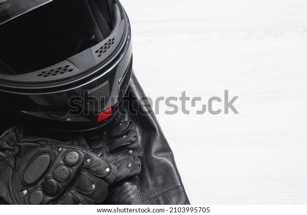 Motorcycle helmet, protective\
gloves and leather jacket on the white table background with copy\
space.