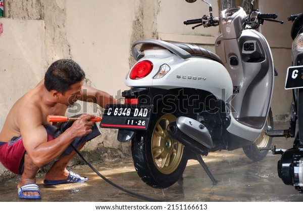 The motorcycle or\
Honda scoopy is being washed or sepeda motor merk honda jenis\
scoopy berwarna putih sedang dibersihkan dan dicuci. Central Java,\
Indonesia, April 30, 2022