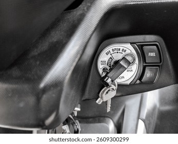 Motorcycle ignition switch with key inserted and fuel-seat control buttons visible in close-up view.