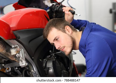 Motorcycle mechanic listening engine noise to find failures in a mechanical workshop - Powered by Shutterstock