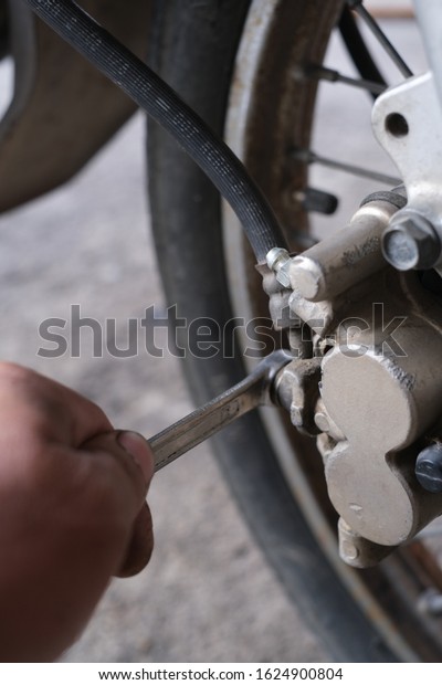 Motorcycle mechanic repairs Motorcycle disc brakes\
on the front.
