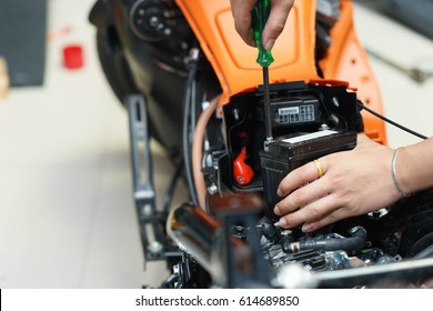 motorcycle mechanic replaces a battery. (maintenance) selective focus - Powered by Shutterstock