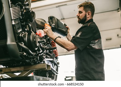 Motorcycle mechanic replacing and pouring fresh oil into engine at maintenance repair service station. Portrait of an auto mechanic putting oil in a car engine.