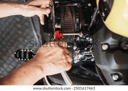 Motorcycle mechanic using Hex key wrench working on motorcycle at motorbike garage , maintenance and repair concept .