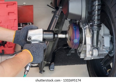 Motorcycle mechanic wearing gloves using air impact wrench and Drive Socket working repair Rear Clutch system of big scooter motorcycle at motorbike garage ,motorcycle maintenance and repair concept, - Powered by Shutterstock