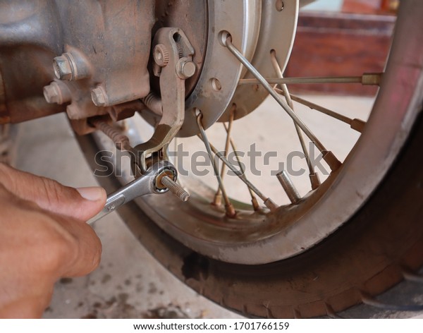 motorcycle mechanic working with wrench in\
garage. Repair\
service.