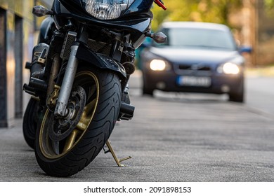 a motorcycle parked on the sidewalk with a blurred city street with cars in the background, selective focus - Shutterstock ID 2091898153