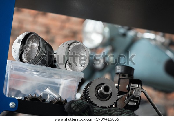 Motorcycle repairing service concept\
background. A car engine piston, gear and wrenches on the rack on\
the old garage\
background.