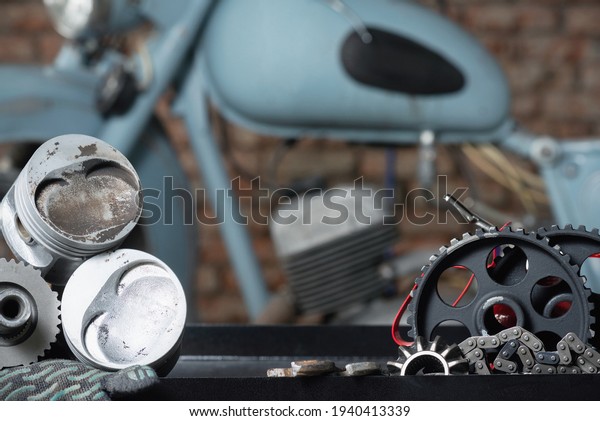 Motorcycle repairing service concept
background. A car engine piston, gear and wrenches on the rack on
the old garage
background.