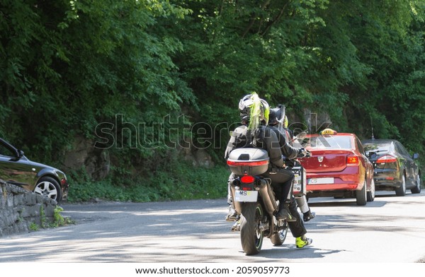 Motorcycle ridden by a couple of motorcyclists in\
jam traffic. Rear view of motorcycle and cars on the street.\
Brasov, Romania, September 29,\
2021