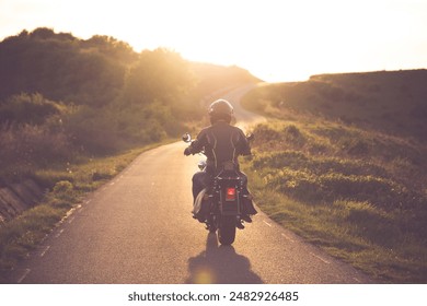 Motorcycle rider on the road in sunset light. Travel and sport, speed and freedom concept.