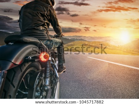 Motorcycle rider ready for drive in Alps, beautiful sunset dramatic sky. Travel and freedom, outdoor activities