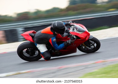 Motorcycle rider riding on a red sport bike through the corner at high speed.