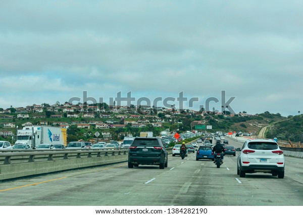 Motorcycle riders passing slower moving traffic by\
riding a motorcycle in the gap between two parallel lanes of\
traffic heading in the same direction - San Diego, California, USA\
- April 22, 2019