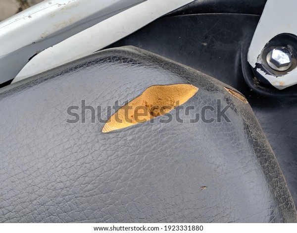 motorcycle\
saddle with torn wrapping and visible\
foam