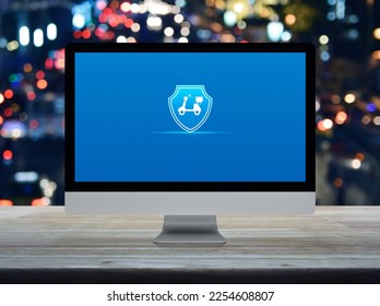 Motorcycle with shield icon on desktop modern computer monitor screen on wooden table over blur colorful night light traffic jam road in city, Business motorcycle insurance online concept - Shutterstock ID 2254608807