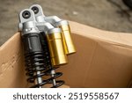 Motorcycle shock absorbers in a cardboard box, showcasing modern design with golden and black details. Perfect for enhancing suspension performance and handling in various riding conditions.