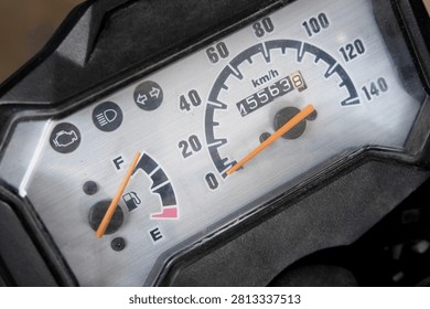 Motorcycle speedometer dashboard close up featuring analog speedometer, fuel gauge, odometer, and indicator warning lights. Detailed motorbike instrument cluster showing vehicle dashboard controls.